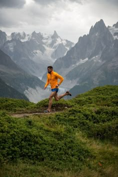 a man is running in the mountains on a cloudy day