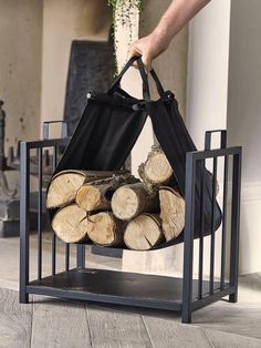 a person holding a black bag over some logs