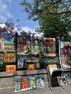 many paintings are on display in front of a fence