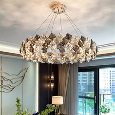 a chandelier hanging from the ceiling in a living room with windows and curtains