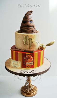 a three tiered cake decorated with hogwart's hat