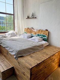 a bed sitting on top of a wooden platform next to a window