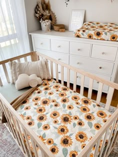 a baby crib with sunflowers on it in a room next to a dresser