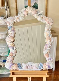 a mirror with seashells on it in front of a wooden table and chair