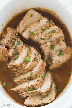 pork stew in a white crock pot with garnishes