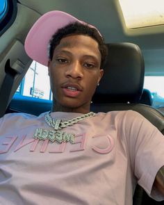 a young man sitting in the back seat of a car with a pink hat on his head