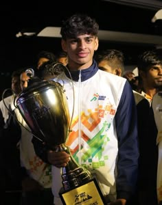 a young man holding up a trophy in front of a crowd