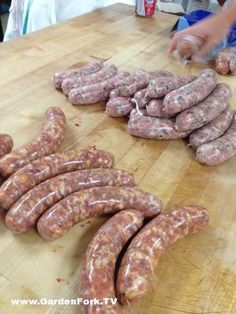 several sausages on a wooden cutting board being cut up by two people in the background