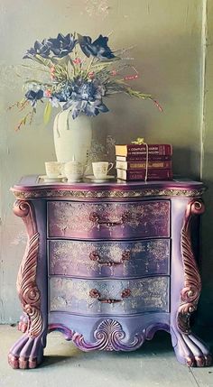 a purple dresser with flowers and books on top