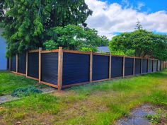 a row of wooden fences sitting next to a green field with trees in the background