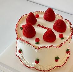 a white cake topped with strawberries on top of a table