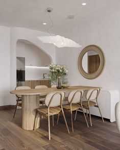 a dining room table and chairs in front of a round mirror on the wall above it