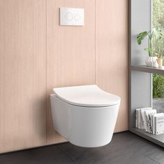 a white toilet sitting next to a window in a room with wooden walls and flooring