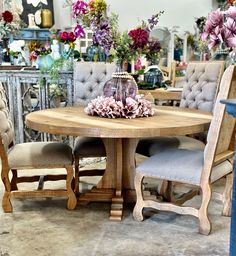 a wooden table with chairs around it in a room filled with flowers and other furniture