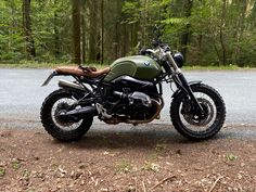 a motorcycle is parked on the side of the road in front of some trees and bushes