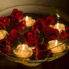 red roses floating in water with lit candles