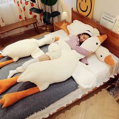 a woman laying on top of a bed covered in giant stuffed ducks next to her