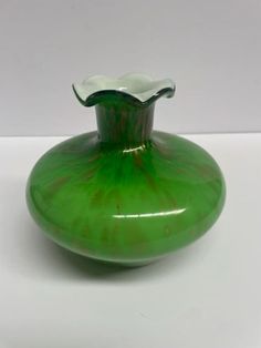 a green vase sitting on top of a white table