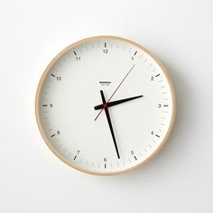 a white clock with black hands and red hands on the face against a white wall