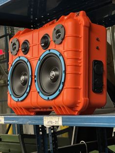 an orange speaker sitting on top of a shelf