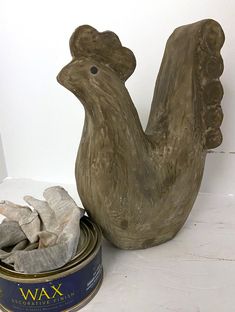 a wooden chicken statue next to a can of wax