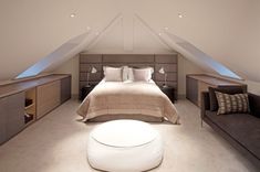 an attic bedroom with bed, couch and storage space in the ceiling is featured on this page