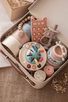 an open suitcase filled with baby toys on top of a floor next to a wall