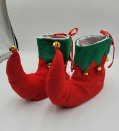 a pair of red and green boots with bells on the soles are sitting next to each other