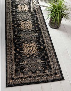 a black and gold rug on the floor next to a potted plant