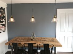 a wooden table with four chairs underneath three hanging lights