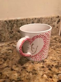 a white coffee cup sitting on top of a counter next to a marble countertop