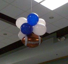 some balloons are hanging from the ceiling in an office building with footballs on them