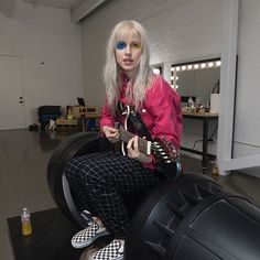 a woman with white hair sitting on top of a black and white couch holding a guitar