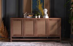 a sideboard with plants on it in front of a painting and other decor items