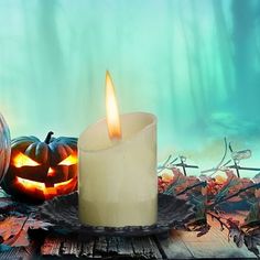 a lit candle sitting on top of a wooden table next to pumpkins and leaves