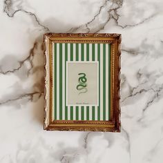 an ornate gold frame with a green and white striped pattern on the wall above it