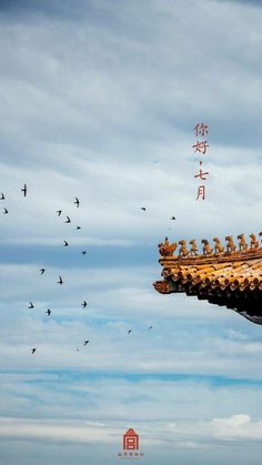 birds flying in the sky over a building with chinese characters on it's roof