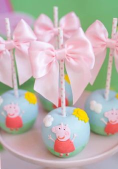 peppa pig cake pops on a plate with pink bows and candy sticks in them