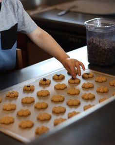 a child reaching for some cookies on a cookie sheet