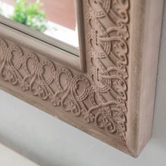 a decorative mirror hanging on the side of a wall next to a window sill