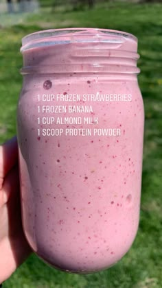 a hand holding a pink smoothie in a mason jar with instructions on how to make it