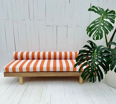 an orange and white striped bench next to a potted plant