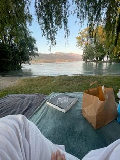 a person laying in a hammock with a book and bag on the ground