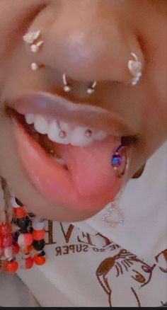 a close up of a child with piercings on her nose and tongue, smiling at the camera