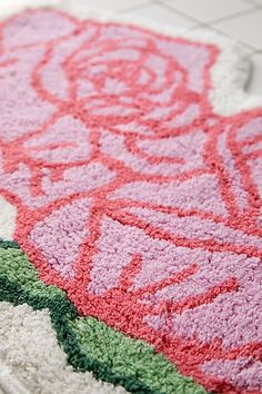 a pink rug with green and red designs on the floor next to a white sink