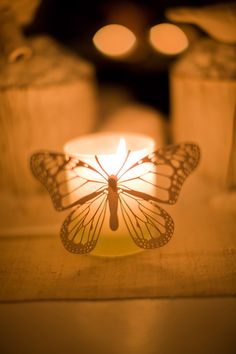 a lit candle with a butterfly on it