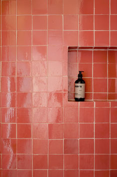 a bathroom with pink tiles and a black bottle