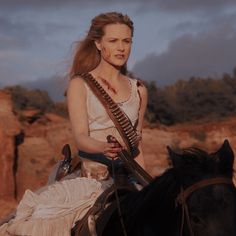 a woman riding on the back of a black horse