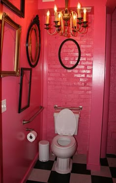 a bathroom with pink walls, black and white checkered flooring and chandelier