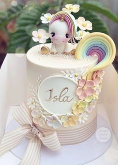 there is a small cake decorated with flowers and a unicorn on it's side